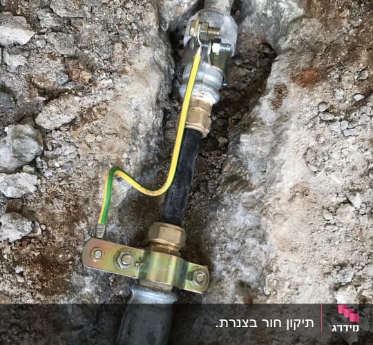 צינור מתכת עם חיבורי ברזל ואדמה חשופה